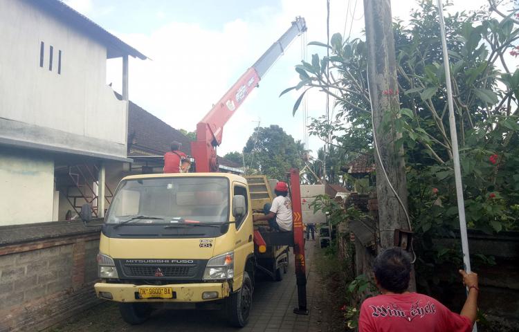 Lengan Baja Turunkan Satu Persatu Material Perbaikan Jalan